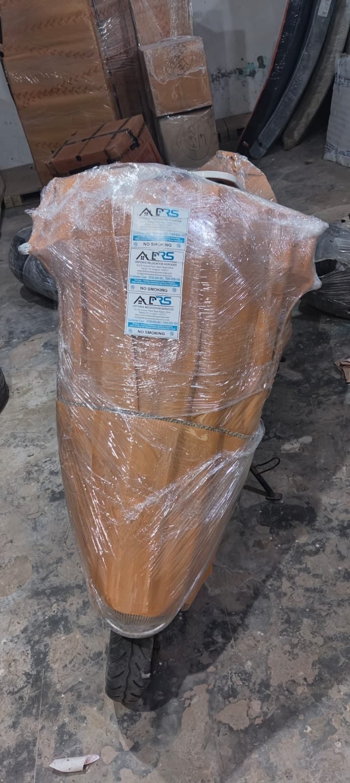 Two-wheeler wrapped and tagged with Defence Relocation Services labels before transport