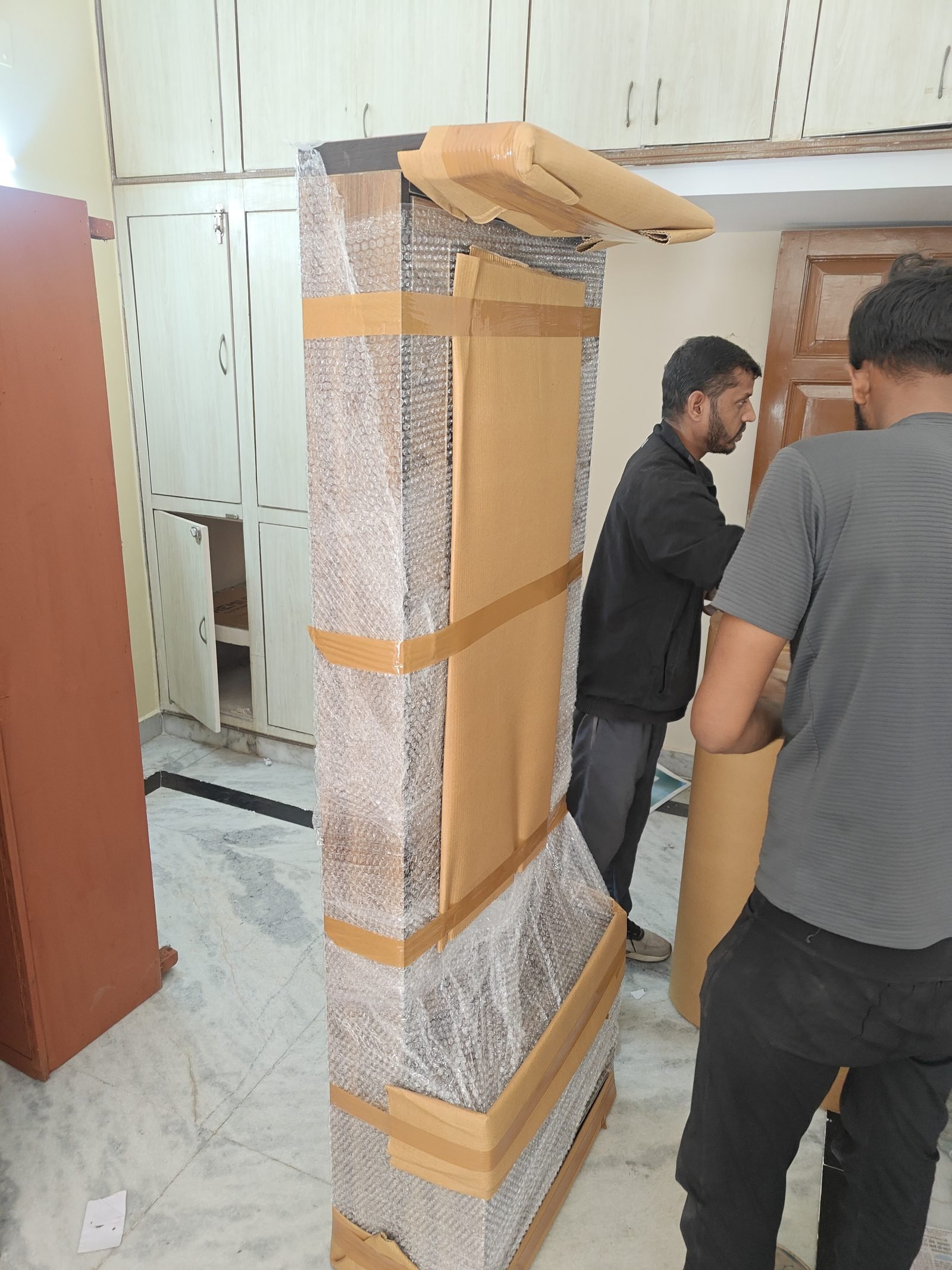 Team wrapping a wardrobe in bubble wrap before loading